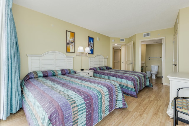 bedroom with ensuite bathroom and light wood-type flooring