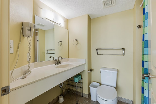 bathroom featuring a textured ceiling, toilet, curtained shower, sink, and tile patterned flooring