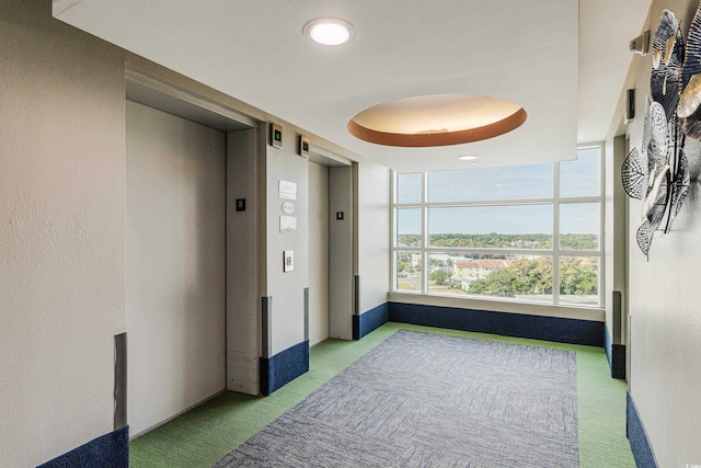 corridor with elevator and light colored carpet