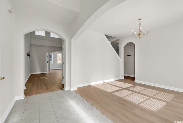 empty room featuring a notable chandelier and light wood-type flooring