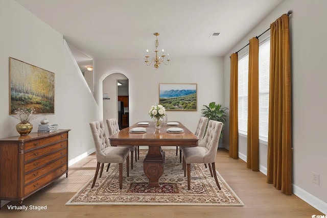 dining area with light wood-type flooring and an inviting chandelier