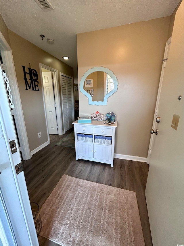 foyer entrance featuring dark wood-type flooring and a textured ceiling