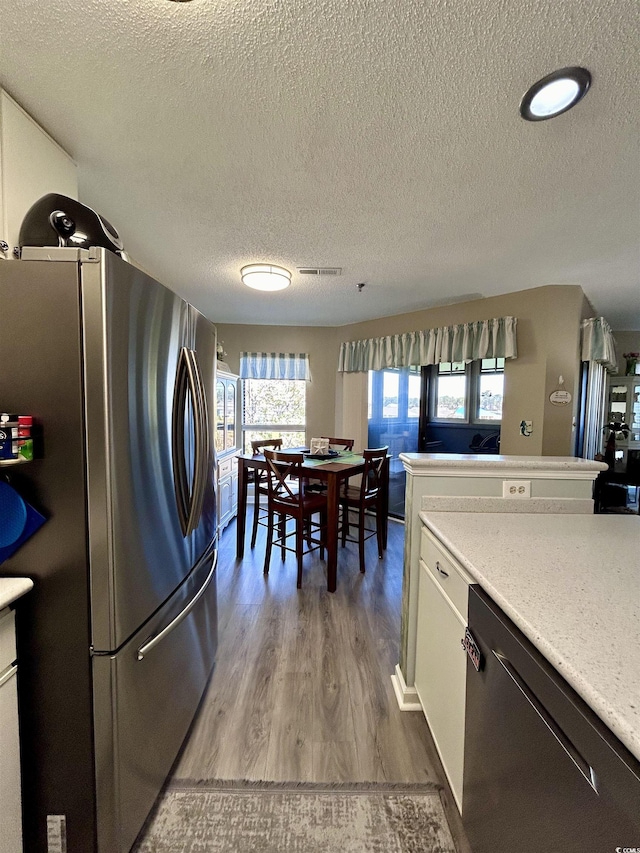 kitchen with a textured ceiling, wood finished floors, stainless steel appliances, and light countertops