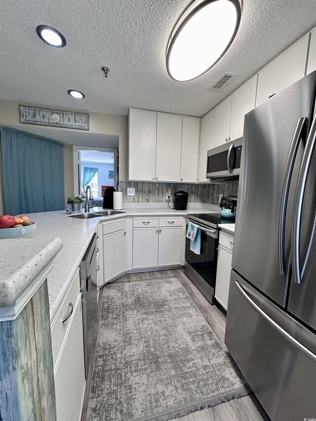 kitchen featuring a sink, appliances with stainless steel finishes, visible vents, light countertops, and light wood finished floors