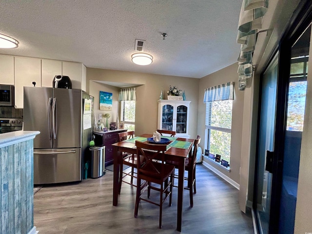 dining room with a healthy amount of sunlight, a textured ceiling, and light hardwood / wood-style flooring