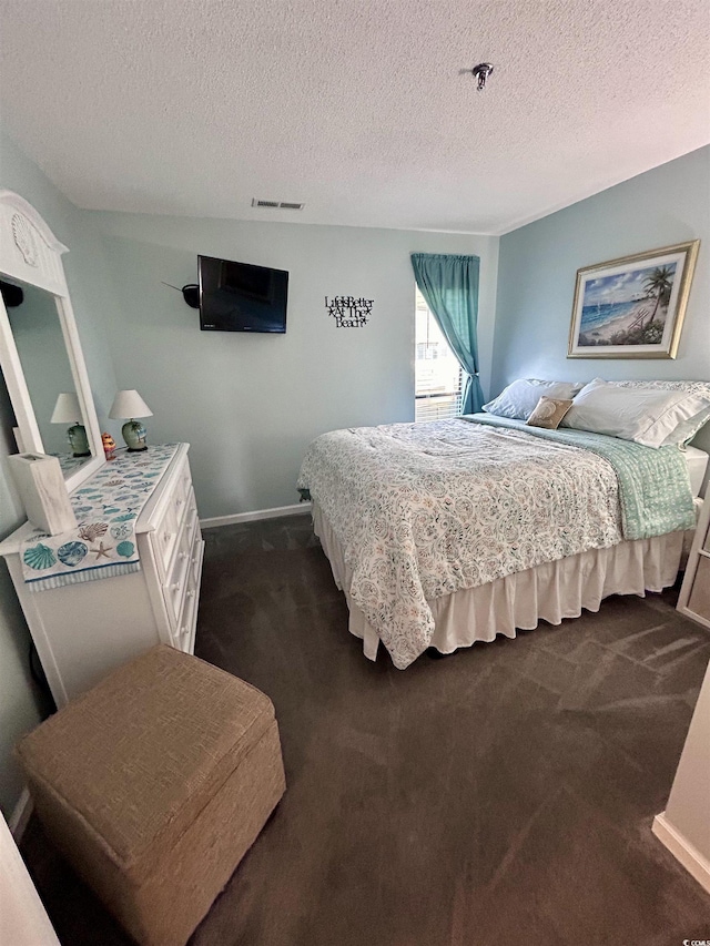 bedroom featuring baseboards, visible vents, dark carpet, and a textured ceiling