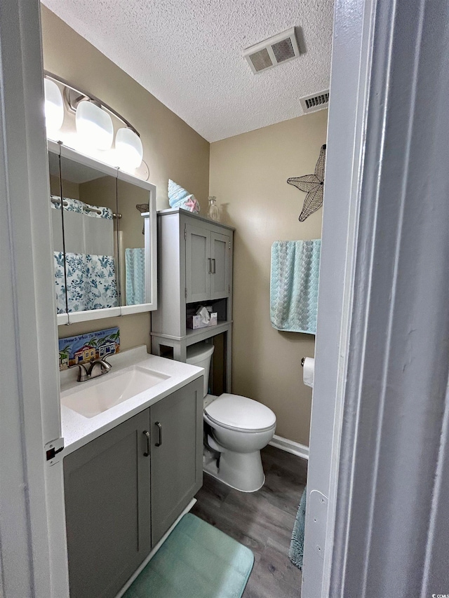 bathroom featuring vanity, a textured ceiling, hardwood / wood-style flooring, and toilet