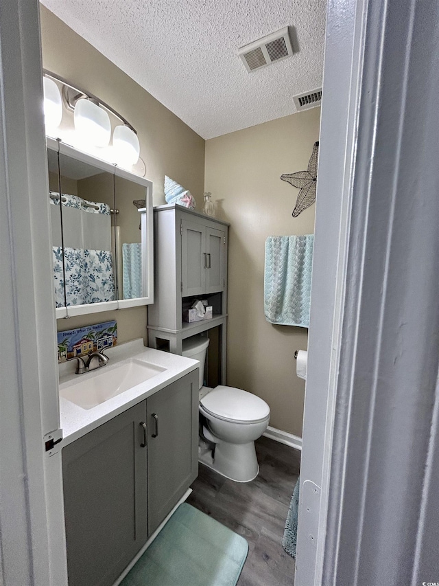 bathroom with toilet, vanity, visible vents, and wood finished floors