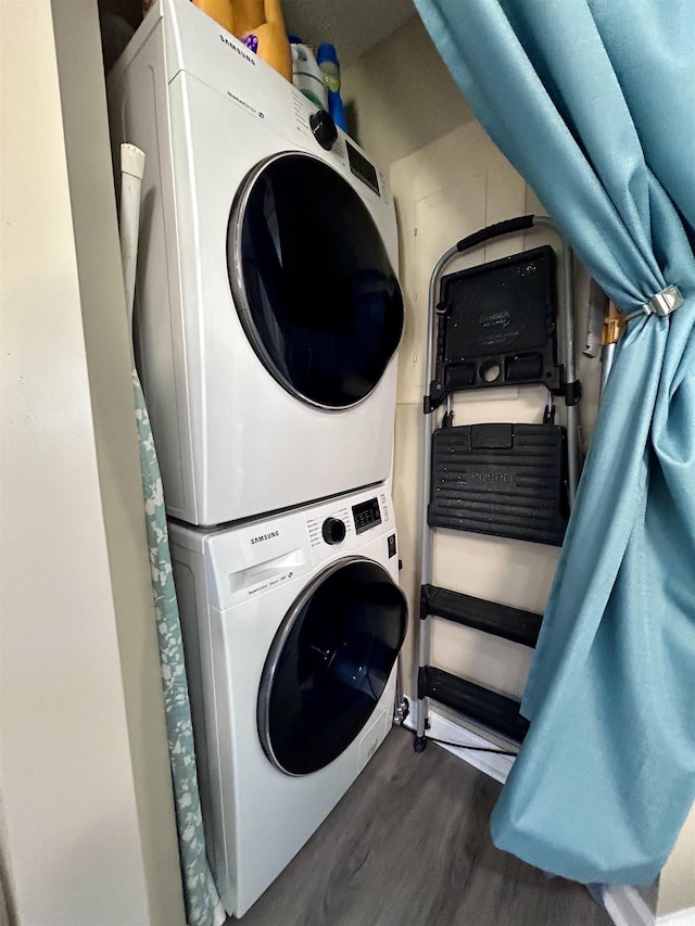 washroom featuring dark wood finished floors, stacked washer and clothes dryer, and laundry area
