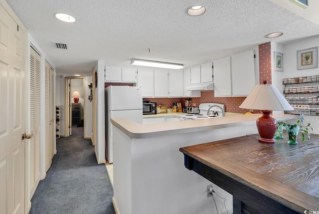 kitchen with kitchen peninsula, white cabinets, a textured ceiling, carpet flooring, and white appliances