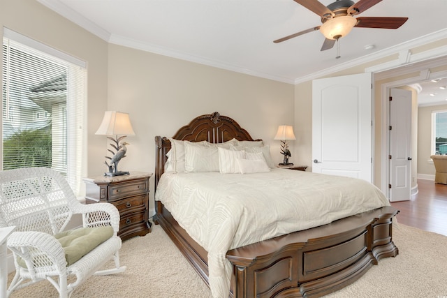 bedroom with ornamental molding, multiple windows, hardwood / wood-style floors, and ceiling fan