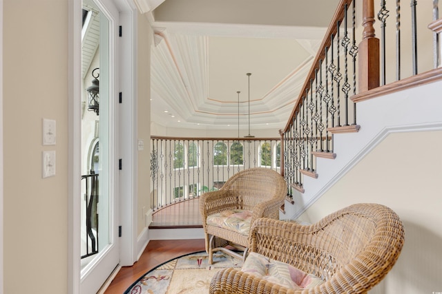 living area with crown molding, hardwood / wood-style flooring, and a raised ceiling