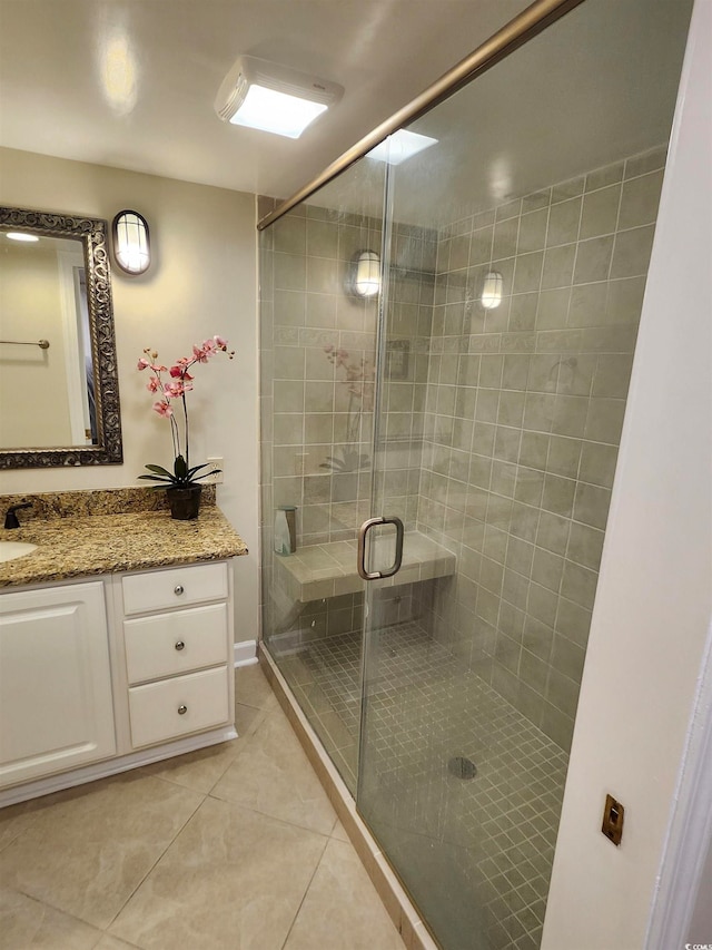 bathroom featuring vanity, a shower with shower door, and tile patterned flooring