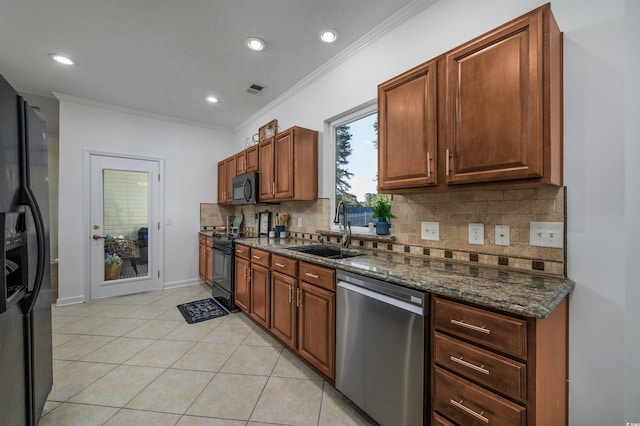 kitchen with decorative backsplash, dark stone countertops, ornamental molding, sink, and black appliances