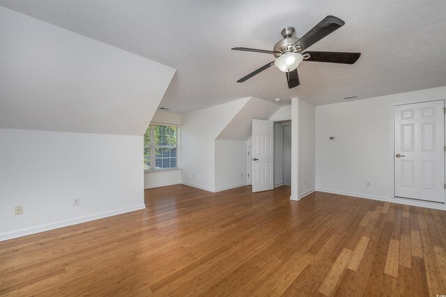 additional living space featuring lofted ceiling, hardwood / wood-style floors, a textured ceiling, and ceiling fan