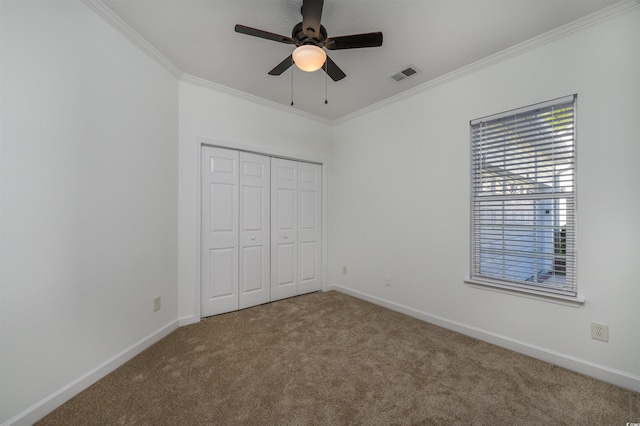 unfurnished bedroom featuring carpet, crown molding, a closet, and ceiling fan