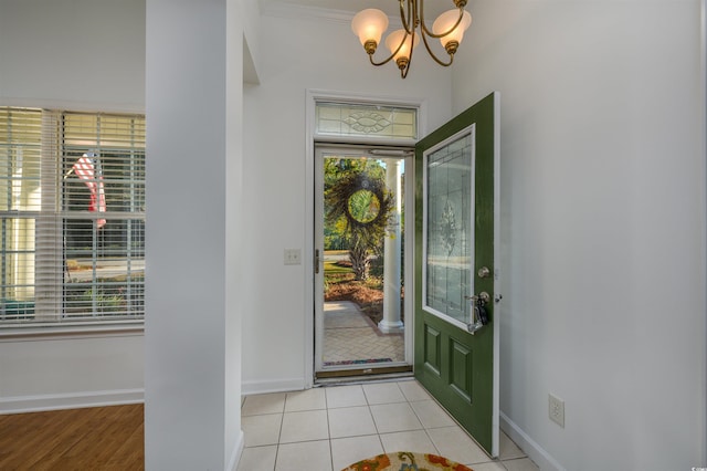 entrance foyer featuring ornamental molding, a chandelier, and light tile patterned floors