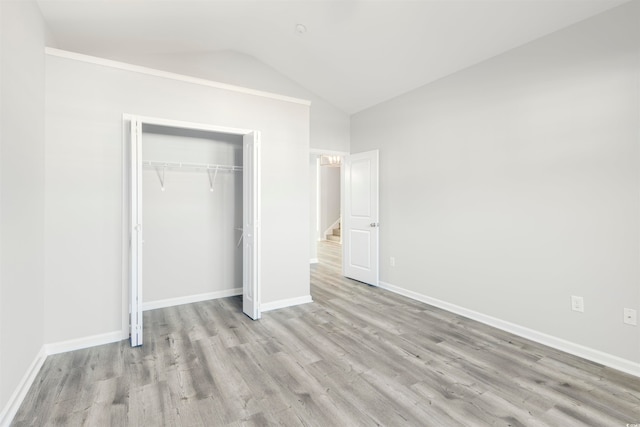 unfurnished bedroom with a closet, vaulted ceiling, and light hardwood / wood-style flooring