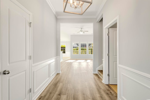 hall featuring ornamental molding, light hardwood / wood-style floors, and a chandelier