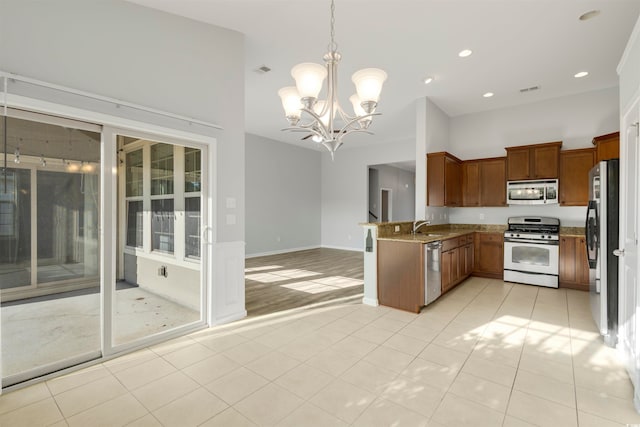 kitchen with appliances with stainless steel finishes, decorative light fixtures, a notable chandelier, sink, and kitchen peninsula