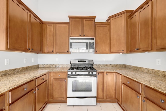 kitchen featuring light tile patterned flooring, light stone counters, and white gas range oven