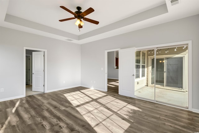 unfurnished room with wood-type flooring, ceiling fan, and a tray ceiling