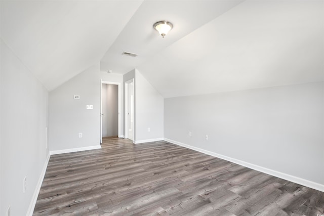 additional living space with hardwood / wood-style floors and vaulted ceiling