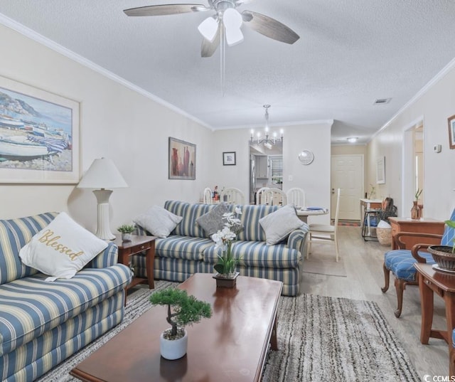 living room with ceiling fan with notable chandelier, light wood-type flooring, a textured ceiling, and ornamental molding