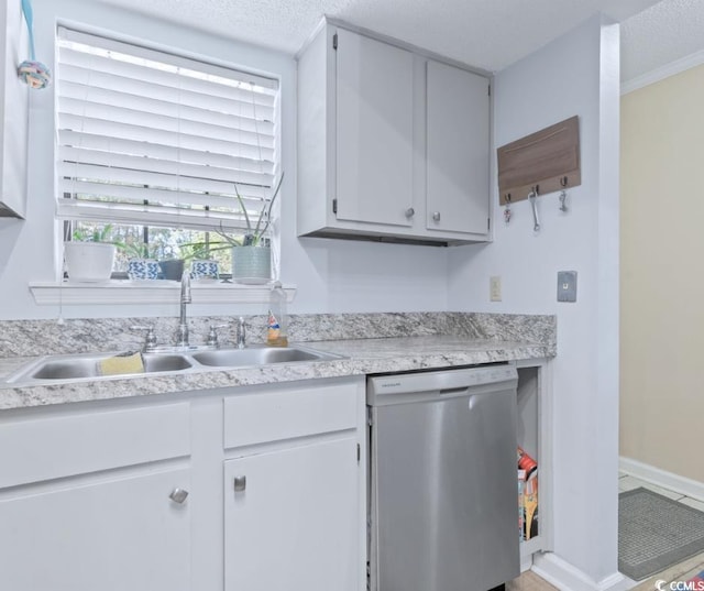 kitchen with white cabinets, a textured ceiling, sink, and stainless steel dishwasher