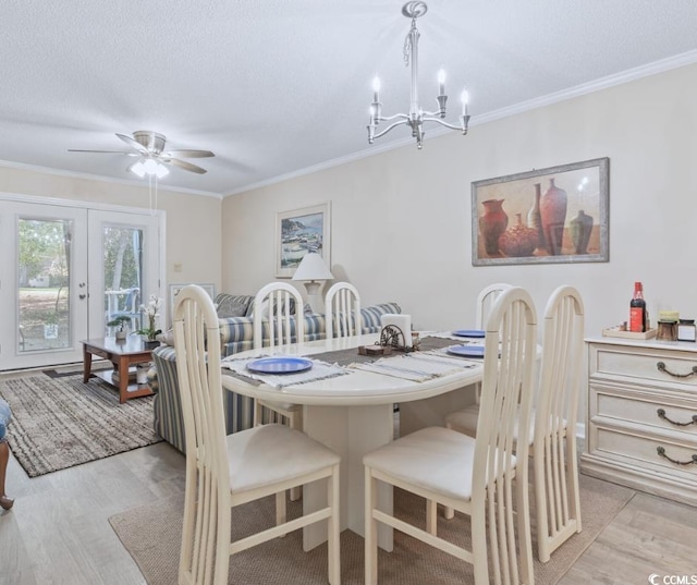 dining space with light wood-type flooring, a textured ceiling, ceiling fan with notable chandelier, crown molding, and french doors