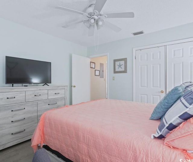 bedroom with dark hardwood / wood-style flooring, ceiling fan, and a closet