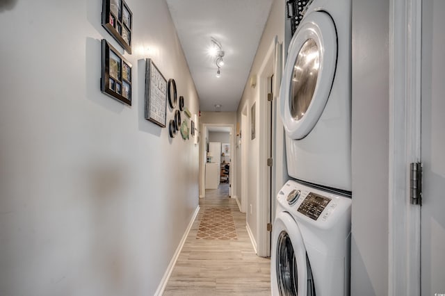 washroom with light hardwood / wood-style flooring and stacked washer / drying machine