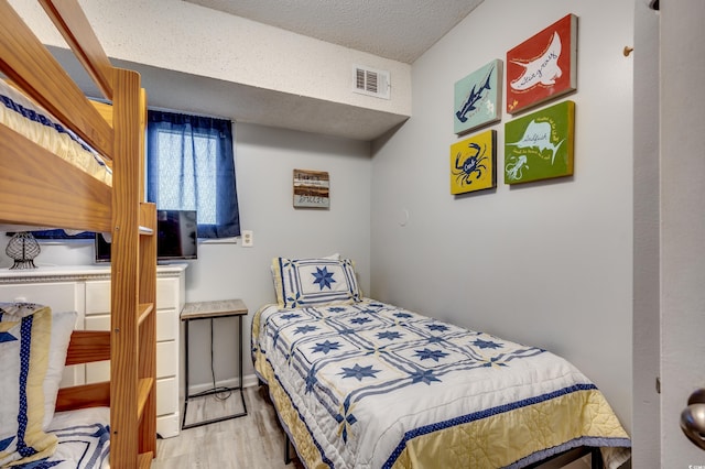 bedroom with a textured ceiling and light hardwood / wood-style floors