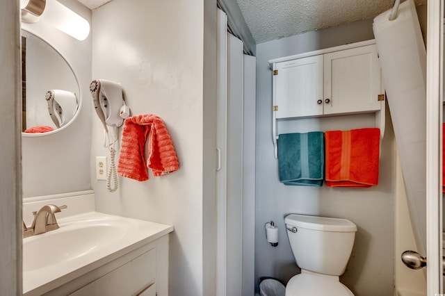 bathroom featuring toilet, a textured ceiling, and vanity