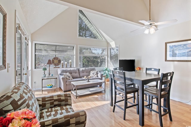 dining room with a textured ceiling, light hardwood / wood-style floors, high vaulted ceiling, and ceiling fan