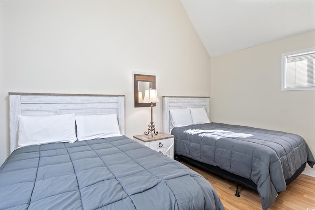 bedroom with high vaulted ceiling and wood-type flooring