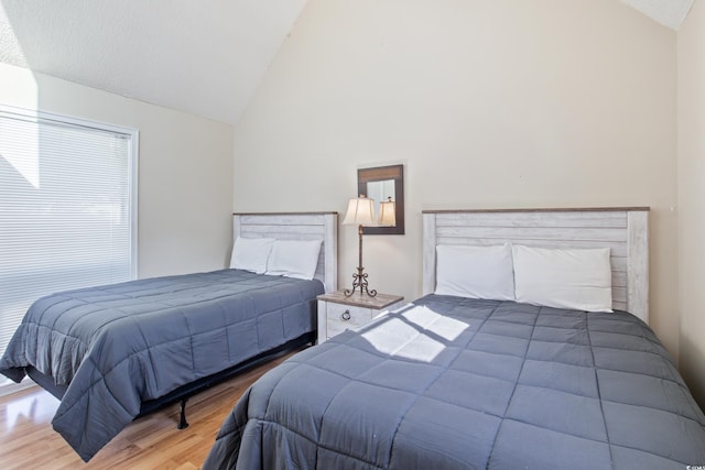 bedroom featuring high vaulted ceiling and hardwood / wood-style flooring