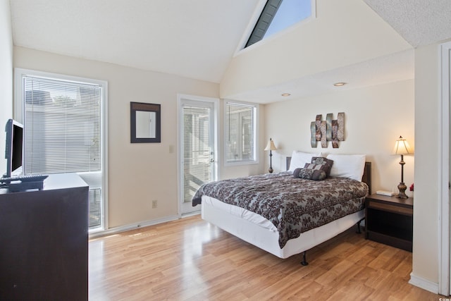 bedroom featuring multiple windows, light hardwood / wood-style floors, and lofted ceiling