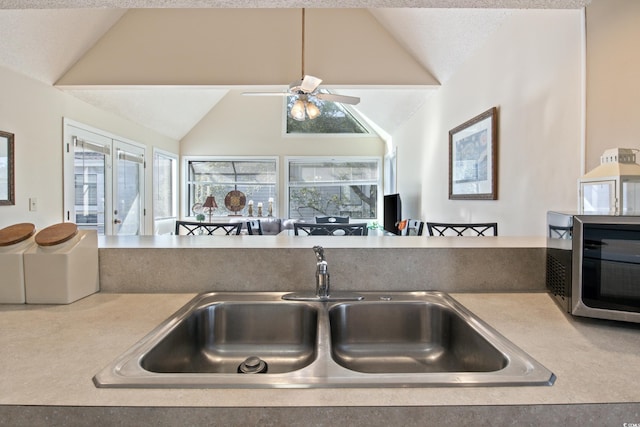 kitchen with a textured ceiling, ceiling fan, sink, and lofted ceiling