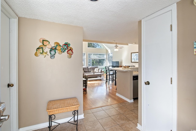 hall featuring light tile patterned floors and a textured ceiling