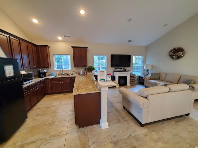 kitchen featuring sink, vaulted ceiling, a wealth of natural light, and black fridge