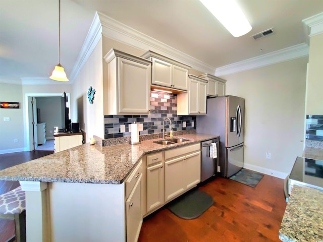 kitchen featuring appliances with stainless steel finishes, sink, cream cabinetry, dark hardwood / wood-style flooring, and decorative light fixtures