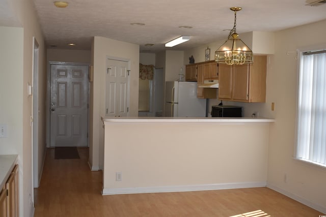 kitchen featuring white fridge, light hardwood / wood-style flooring, decorative light fixtures, and an inviting chandelier