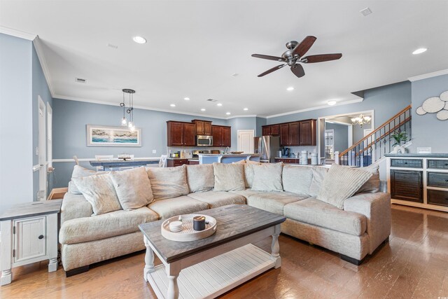 living room with crown molding, wood-type flooring, and ceiling fan with notable chandelier