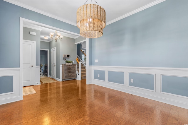 empty room with ornamental molding, an inviting chandelier, and hardwood / wood-style floors