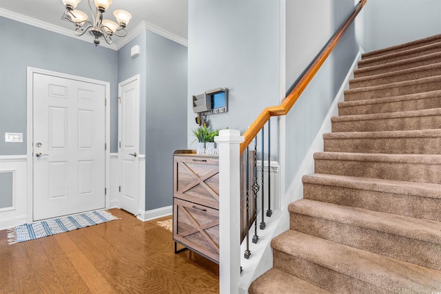 entryway with ornamental molding, a notable chandelier, and wood-type flooring