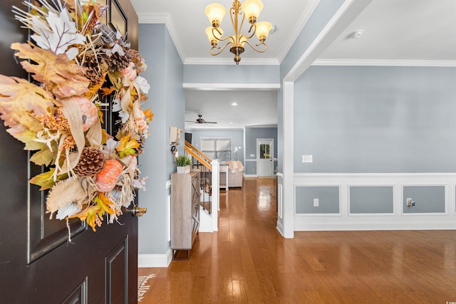 entrance foyer with ornamental molding, hardwood / wood-style floors, and ceiling fan with notable chandelier