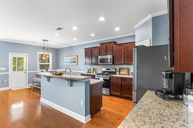 kitchen featuring light stone countertops, appliances with stainless steel finishes, a kitchen bar, light hardwood / wood-style floors, and crown molding