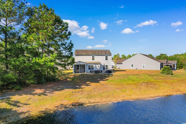 rear view of house featuring a water view and a lawn