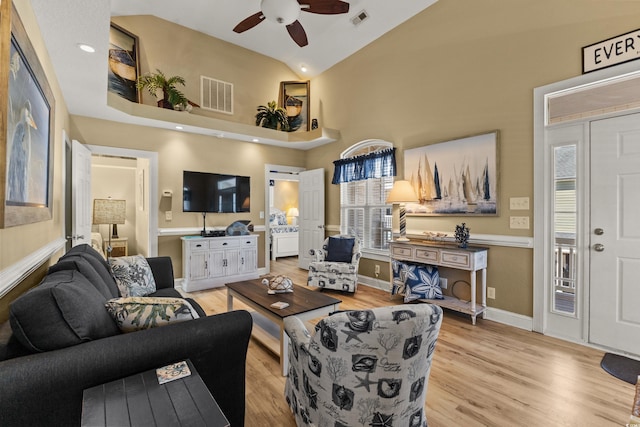 living room with ceiling fan, high vaulted ceiling, and light wood-type flooring